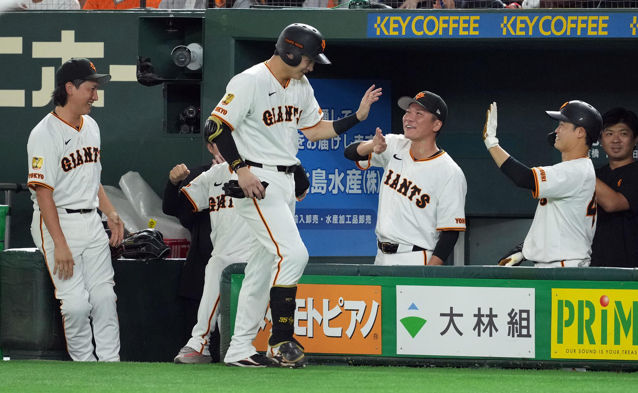 巨人対中日　6回裏巨人無死一塁、四球を選び出塁した泉口は、代走を出されベンチに戻りナインとハイタッチを交わす（撮影・たえ見朱実）