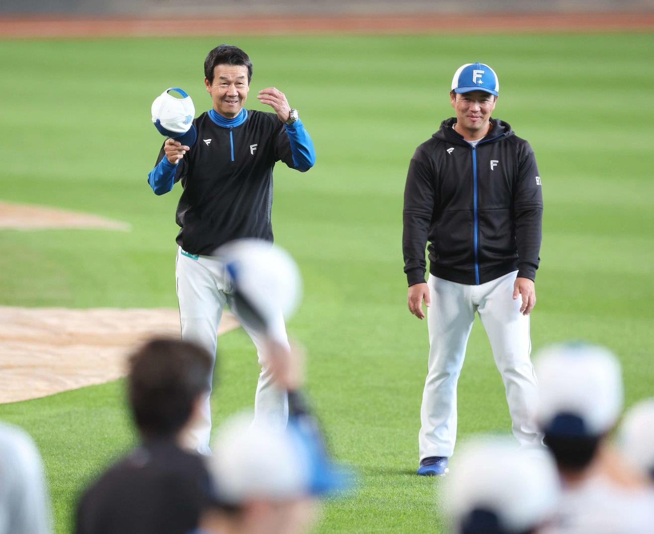 チームに合流し選手に拍手され笑顔の日本ハム八木打撃コーチ（左）（撮影・黒川智章）