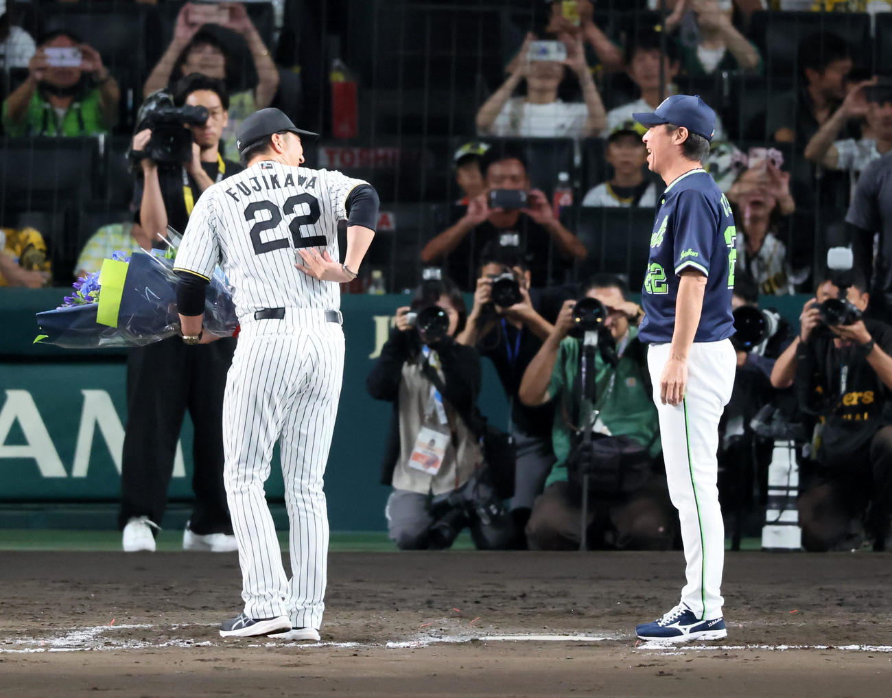 阪神対ヤクルト　試合後ヤクルト高津監督に花束を手渡す阪神藤川監督（左）は背中の背番号22を見せて言葉をかける（撮影・加藤哉）