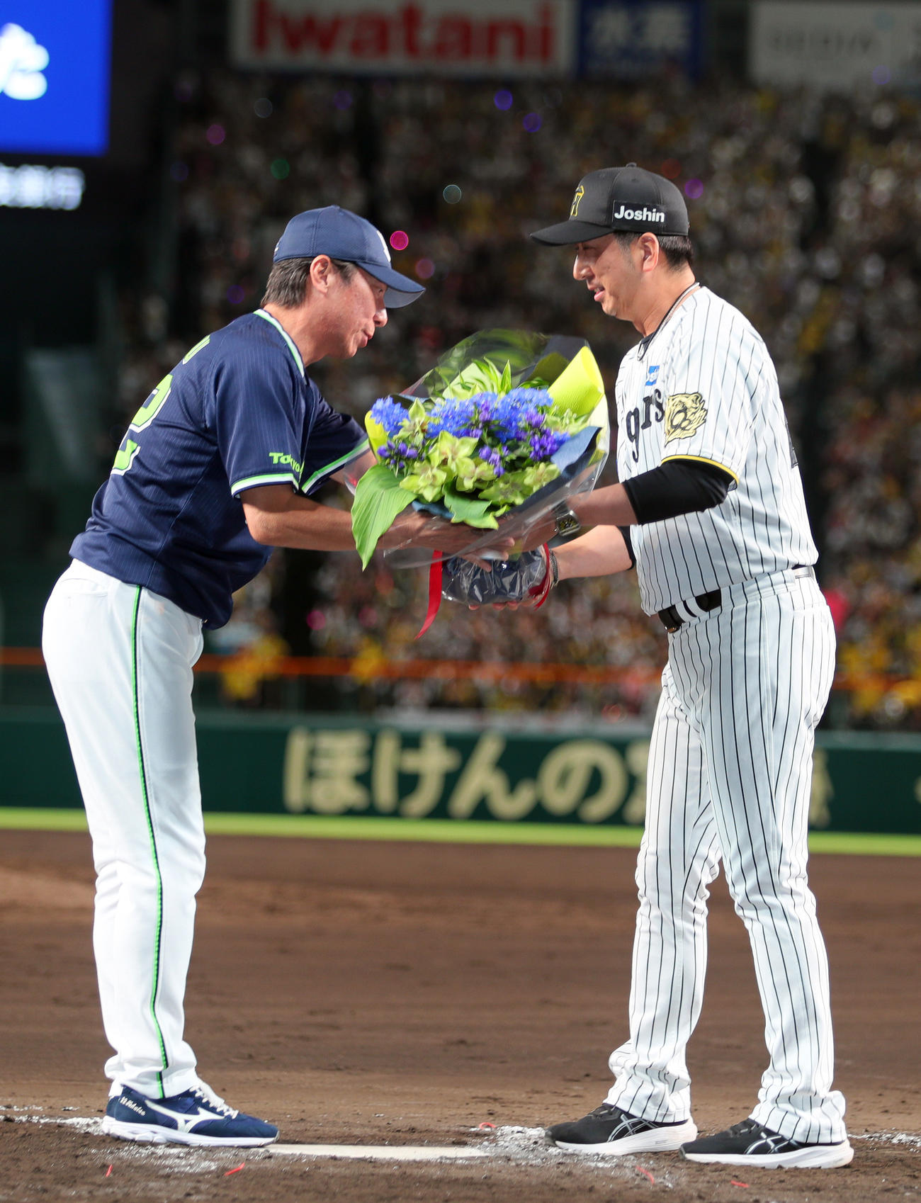 阪神対ヤクルト　今シーズン限りで退任するヤクルト高津監督（左）に花束を渡す阪神藤川監督（撮影・上山淳一）
