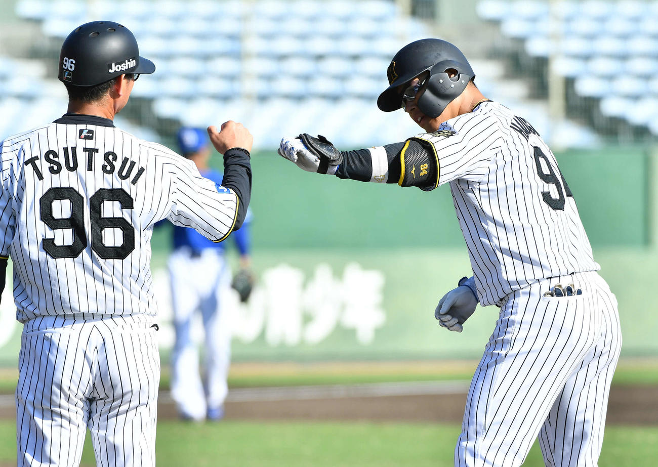 阪神対中日　7回裏阪神2死、左前安打で出塁した原口（右）は筒井コーチとグータッチを交わす（撮影・岩下翔太）