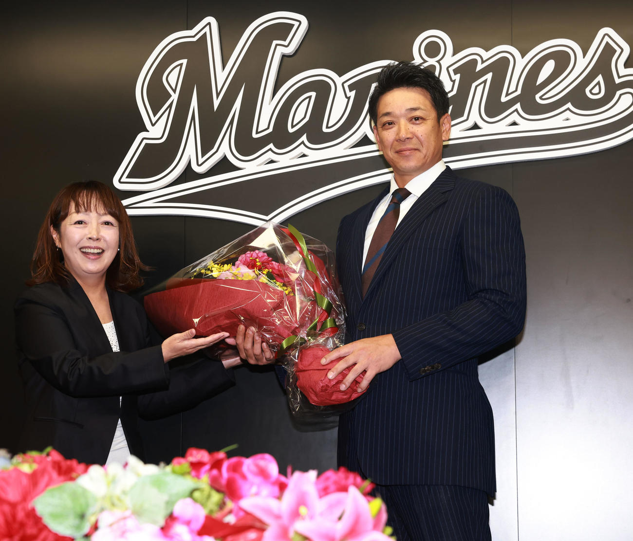 就任会見で元場内アナウンス担当の谷保さん（左）から花束をもらうロッテのサブロー新監督（撮影・野上伸悟）