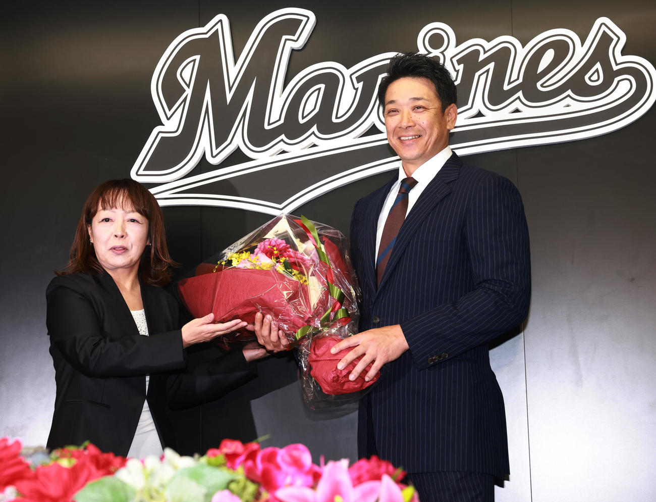 就任会見で元場内アナウンス担当の谷保さん（左）から花束をもらうロッテのサブロー新監督（撮影・野上伸悟）