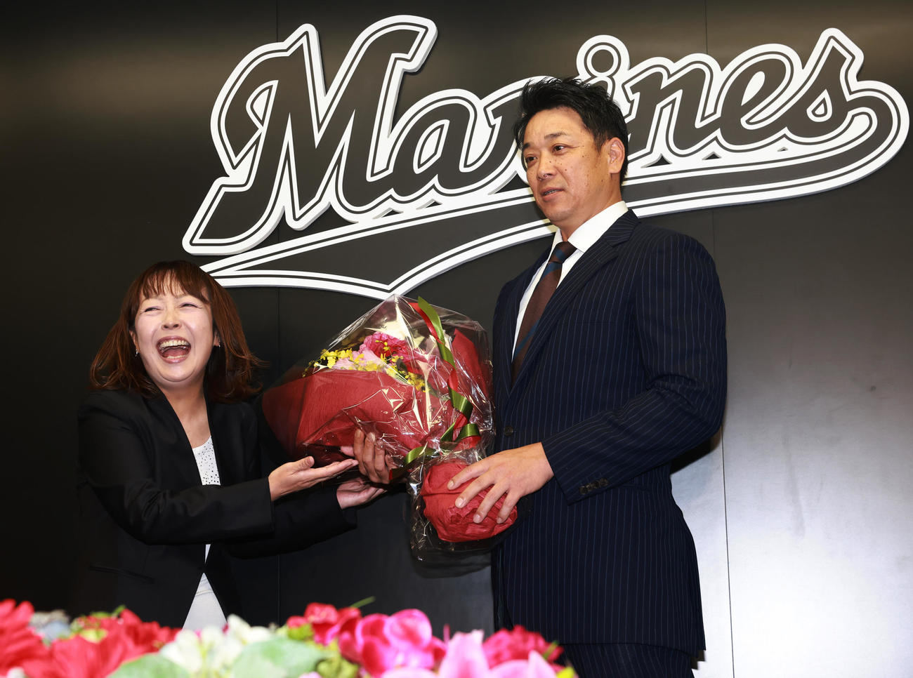就任会見で元場内アナウンス担当の谷保さん（左）から花束をもらうロッテのサブロー新監督（撮影・野上伸悟）