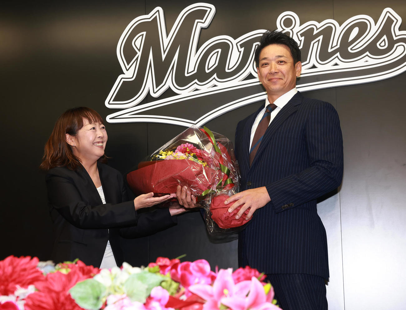 就任会見で元場内アナウンス担当の谷保さん（左）から花束をもらうロッテのサブロー新監督（撮影・野上伸悟）