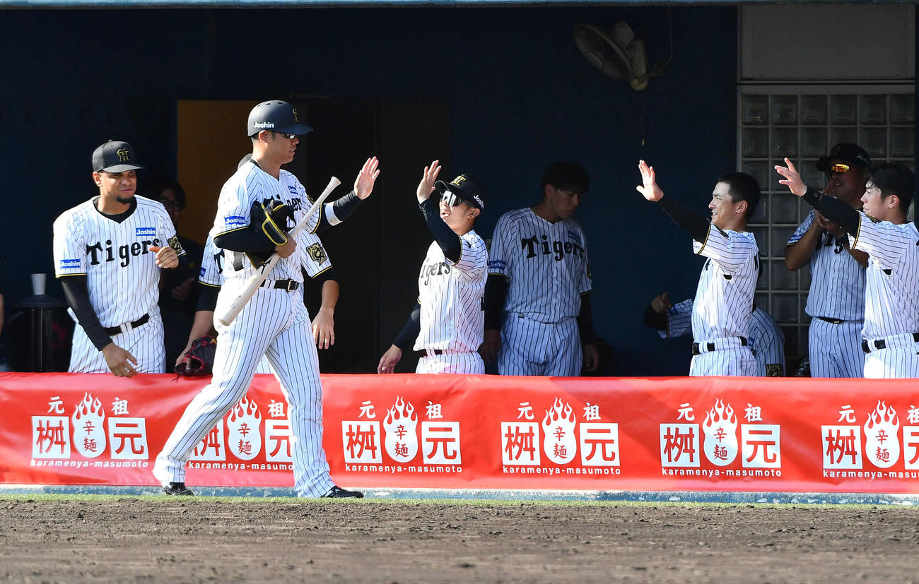 阪神対くふうハヤテ　9回裏阪神1死二塁、同点の左前適時打を放った原口（左から2人目）は代走を送られ、ベンチ前でナインとタッチを交わす（撮影・岩下翔太）