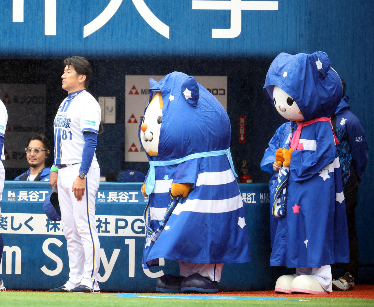 DeNA対巨人　試合前、雨具を着けたマスコットと並んで君が代斉唱するDeNA三浦監督（撮影・浅見桂子）
