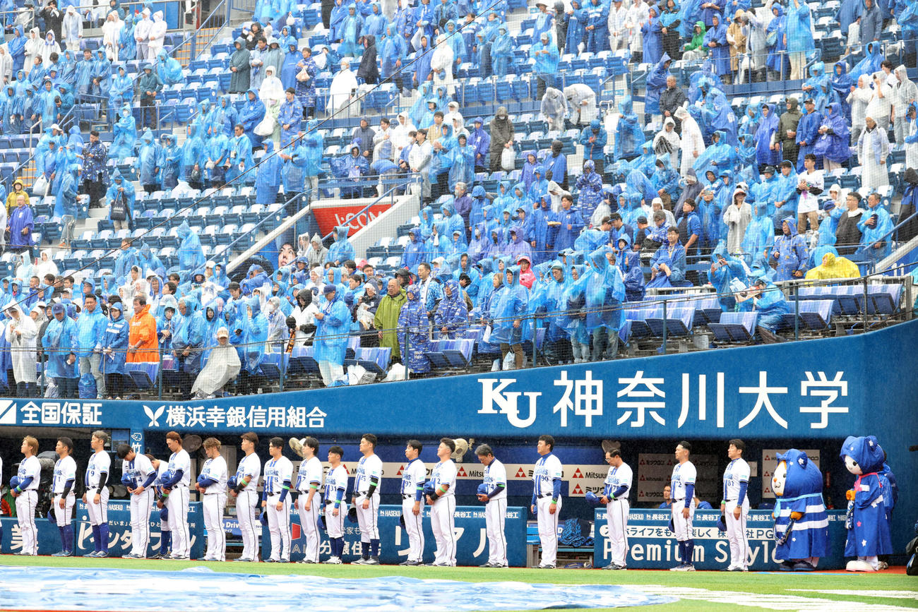 DeNA対巨人　試合前、雨具を着けたマスコットと並んで君が代斉唱するDeNA三浦監督（右）ら選手たち（撮影・浅見桂子）