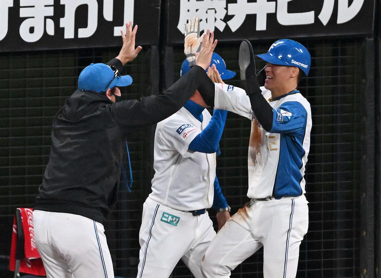 日本ハム対オリックス　8回裏日本ハム2死一、二塁、レイエスの2点適時打で生還した一塁走者矢沢（右）とハイタッチする新庄監督（撮影・滝沢徹郎）