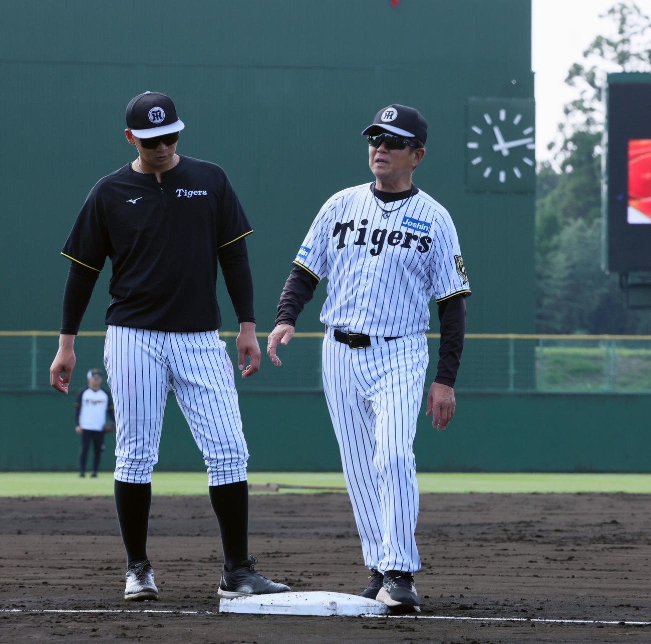 阪神対ヤクルト　今回試験導入されている四隅に突起物がある新型の大きいベースを確認する阪神平田2軍監督。左は井上（撮影・加藤哉）