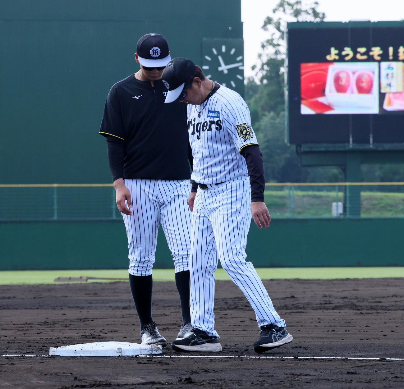 阪神対ヤクルト　今回試験導入されている四隅に突起物がある新型の大きいベースを確認する阪神平田2軍監督。左は井上（撮影・加藤哉）