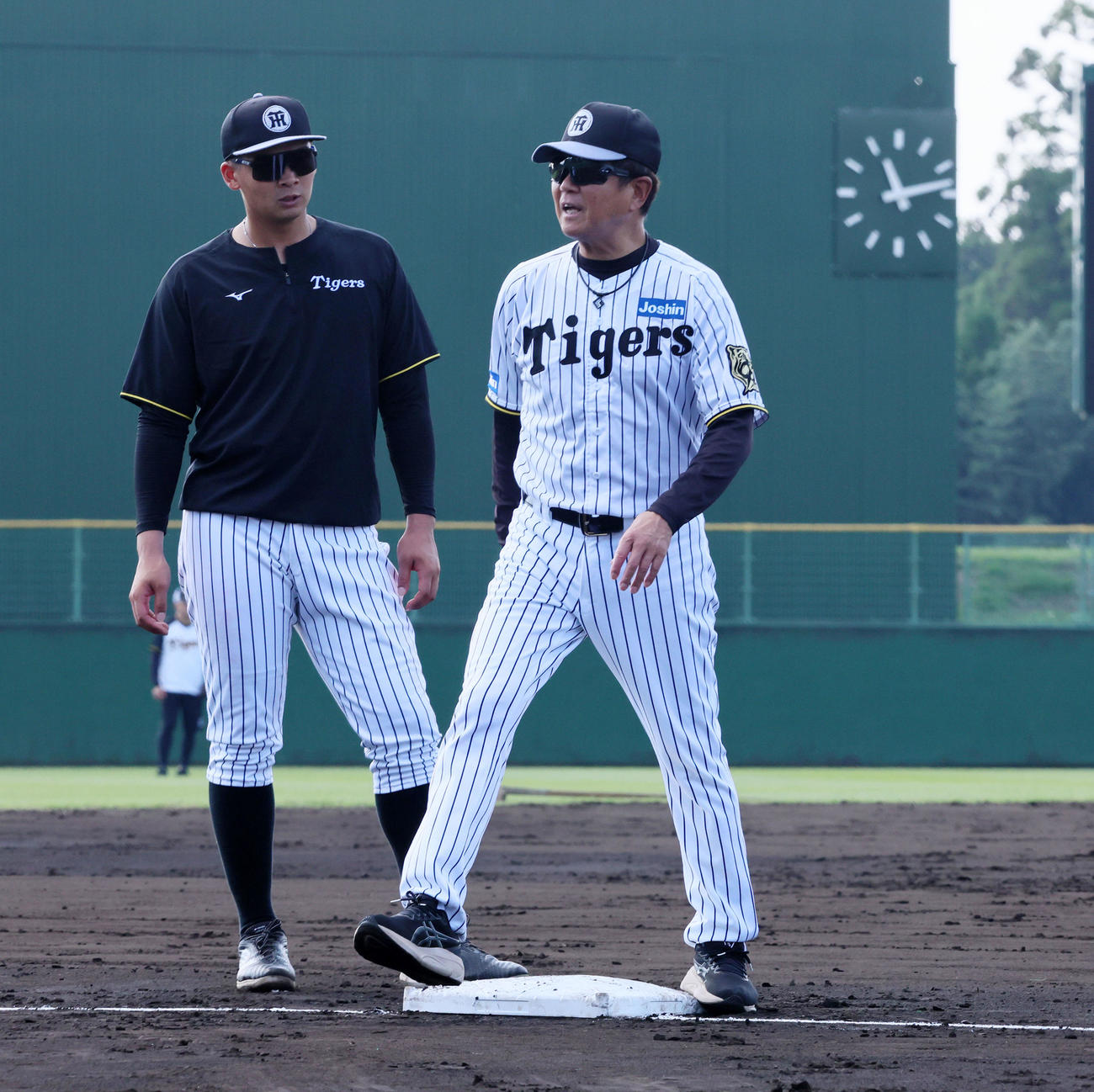 阪神対ヤクルト　今回試験導入されている四隅に突起物がある新型の大きいベースを確認する阪神平田2軍監督。左は井上（撮影・加藤哉）