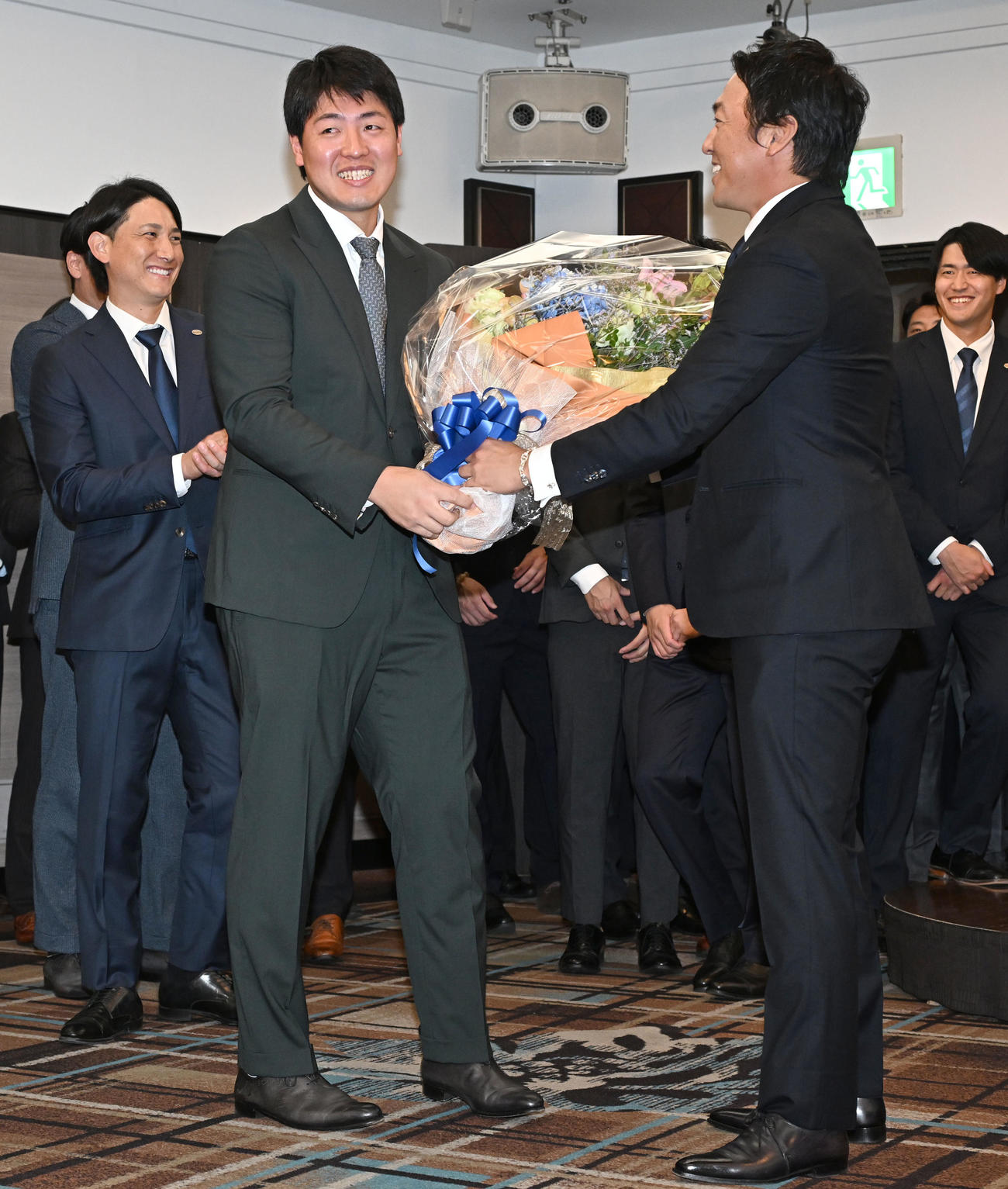 現役引退記者会見を終えた巨人長野外野手から逆に花束を渡され苦笑いを浮かべる岡本（手前左）（撮影・千葉一成）