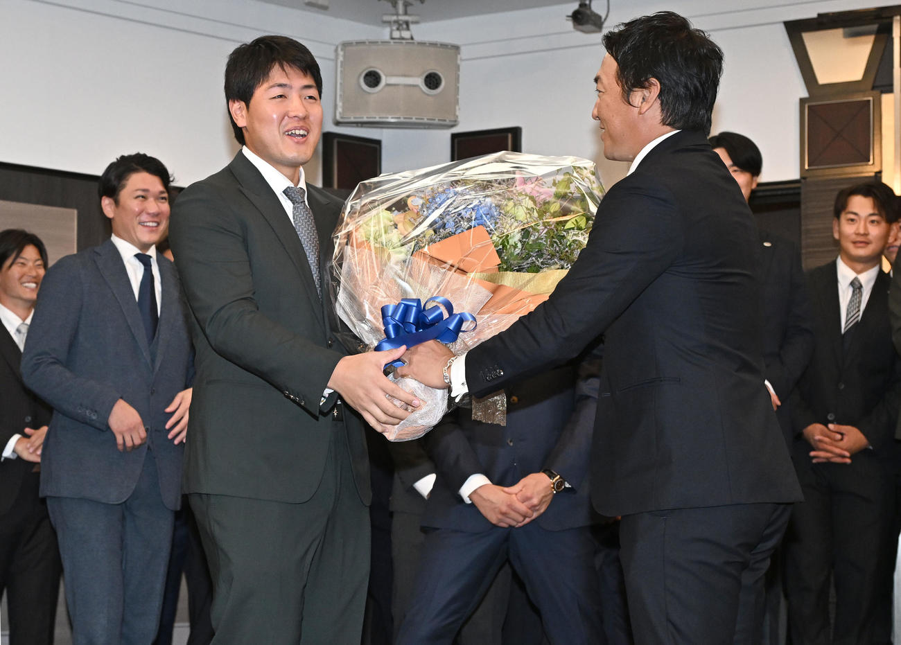 現役引退記者会見を終えた巨人長野外野手から逆に花束を渡され苦笑いを浮かべる岡本（手前左）（撮影・千葉一成）