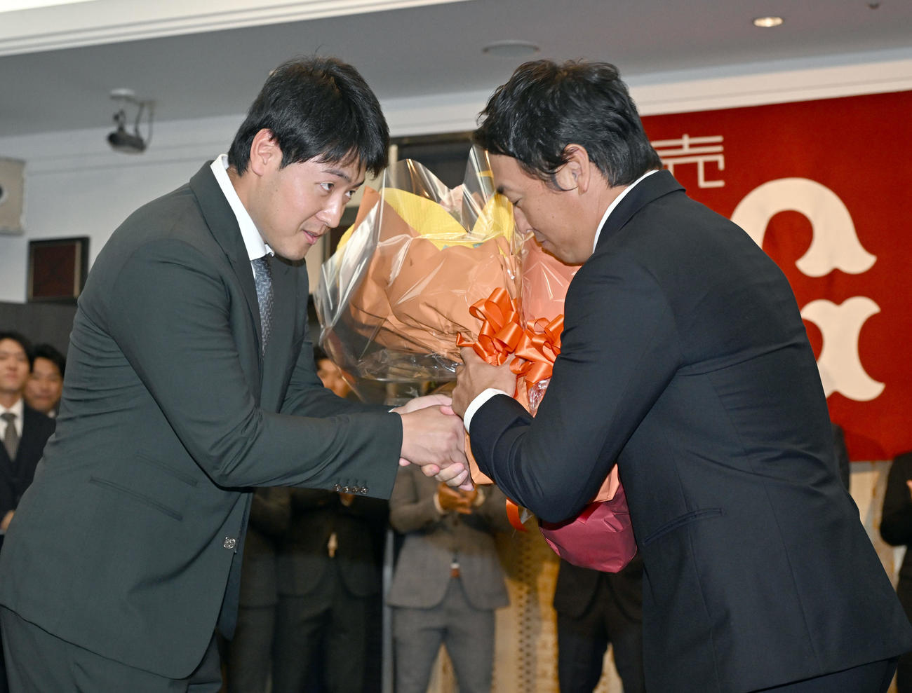 現役引退記者会見に駆けつけた岡本和真（左か）から花束を受け取る巨人長野外野手（撮影・千葉一成）