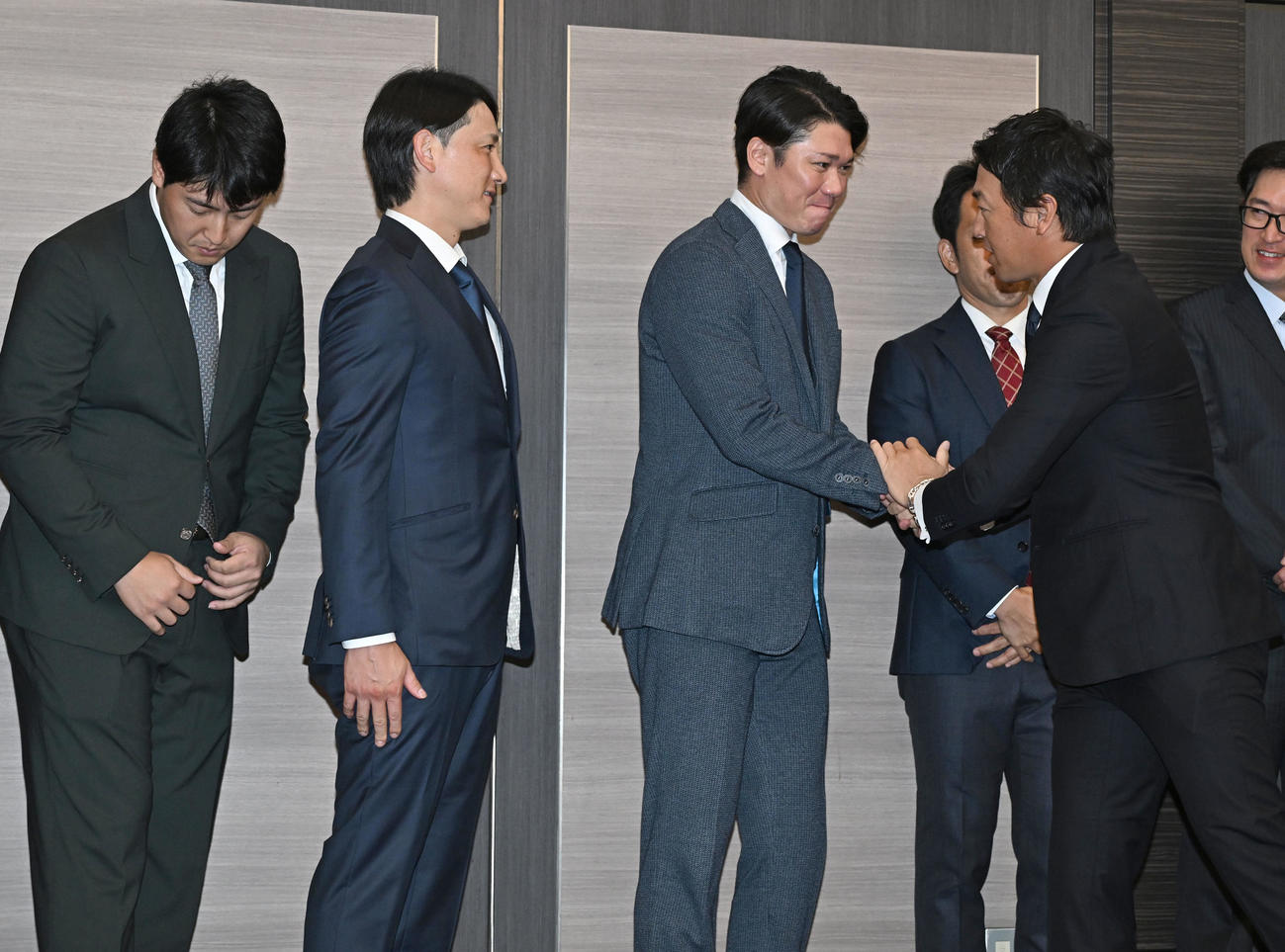 現役引退記者会見に駆けつけ巨人長野（右手前）と握手で別れを惜しむ坂本（左から3人目）ら（撮影・千葉一成）