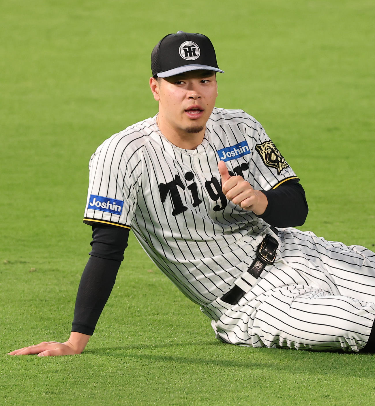 ストレッチ中にサムズアップポーズを見せる佐藤輝（撮影・上田博志）