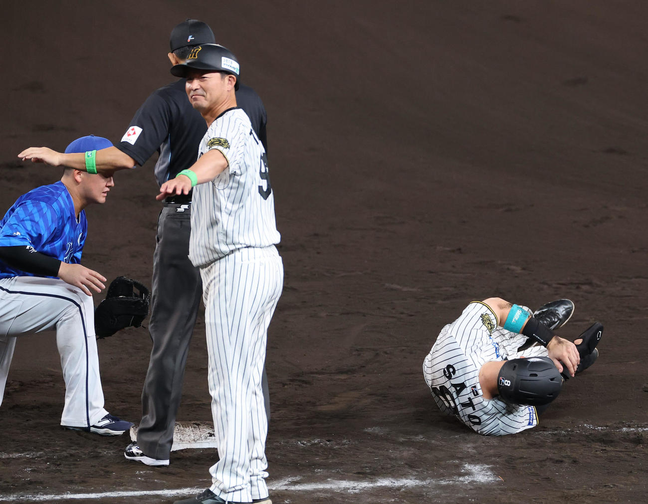 阪神対DeNA 8回裏阪神1死一塁、けん制球が当たり倒れ込む佐藤輝（撮影・上田博志）