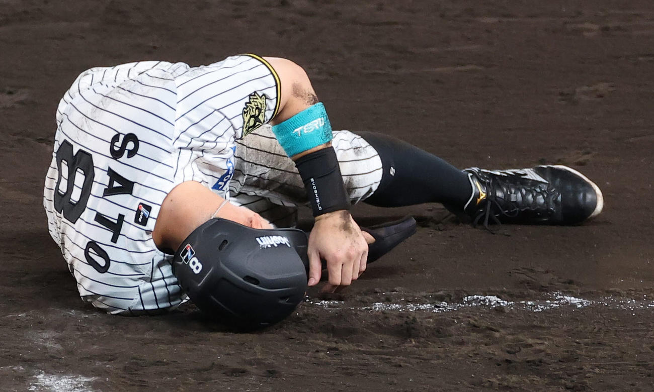 阪神対DeNA 8回裏阪神1死一塁、けん制球が当たり倒れ込む佐藤輝（撮影・上田博志）