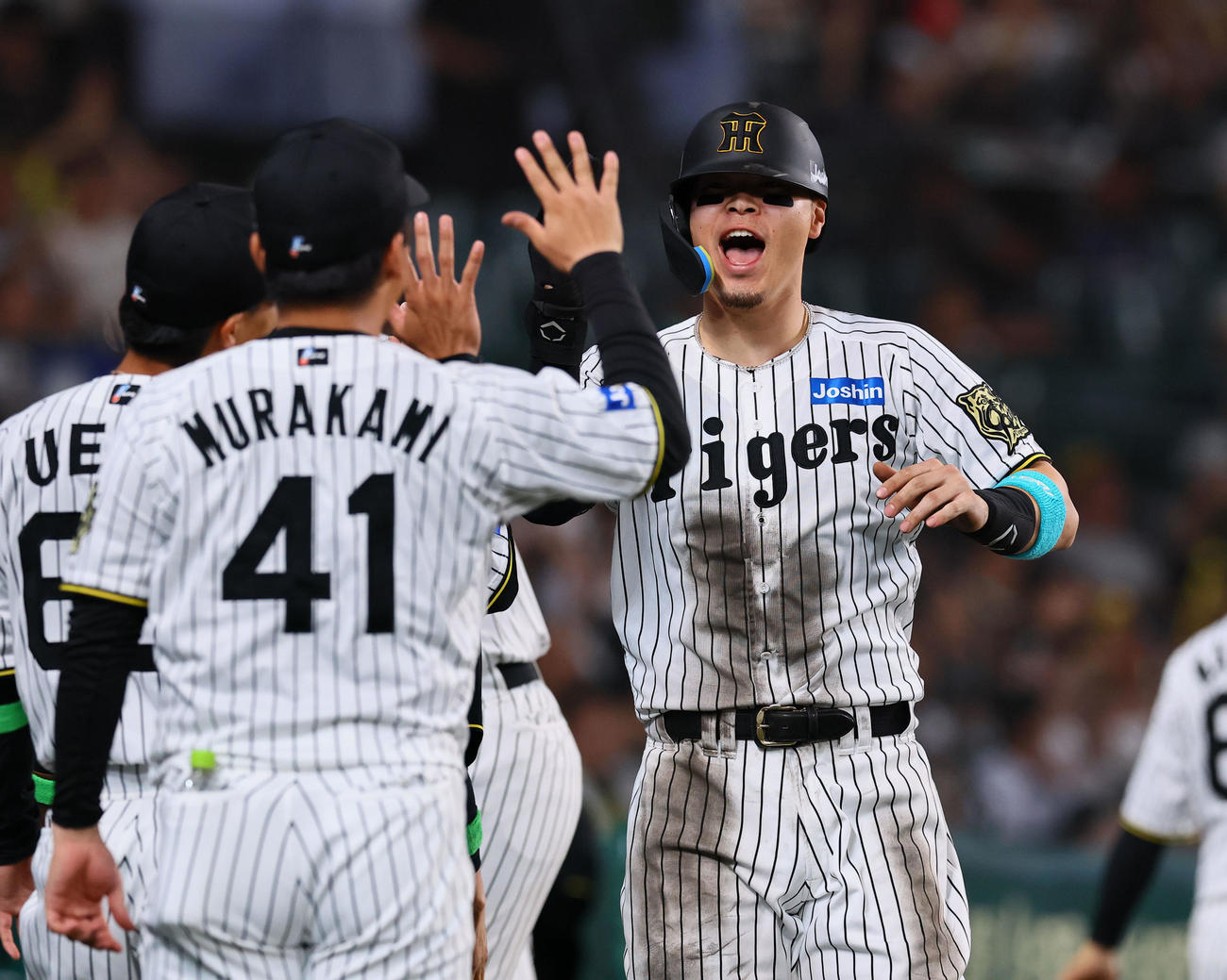 阪神対DeNA 6回裏阪神2死一、三塁、小野寺の右前適時打で生還し、ナインとタッチを交わす佐藤輝（撮影・藤尾明華）