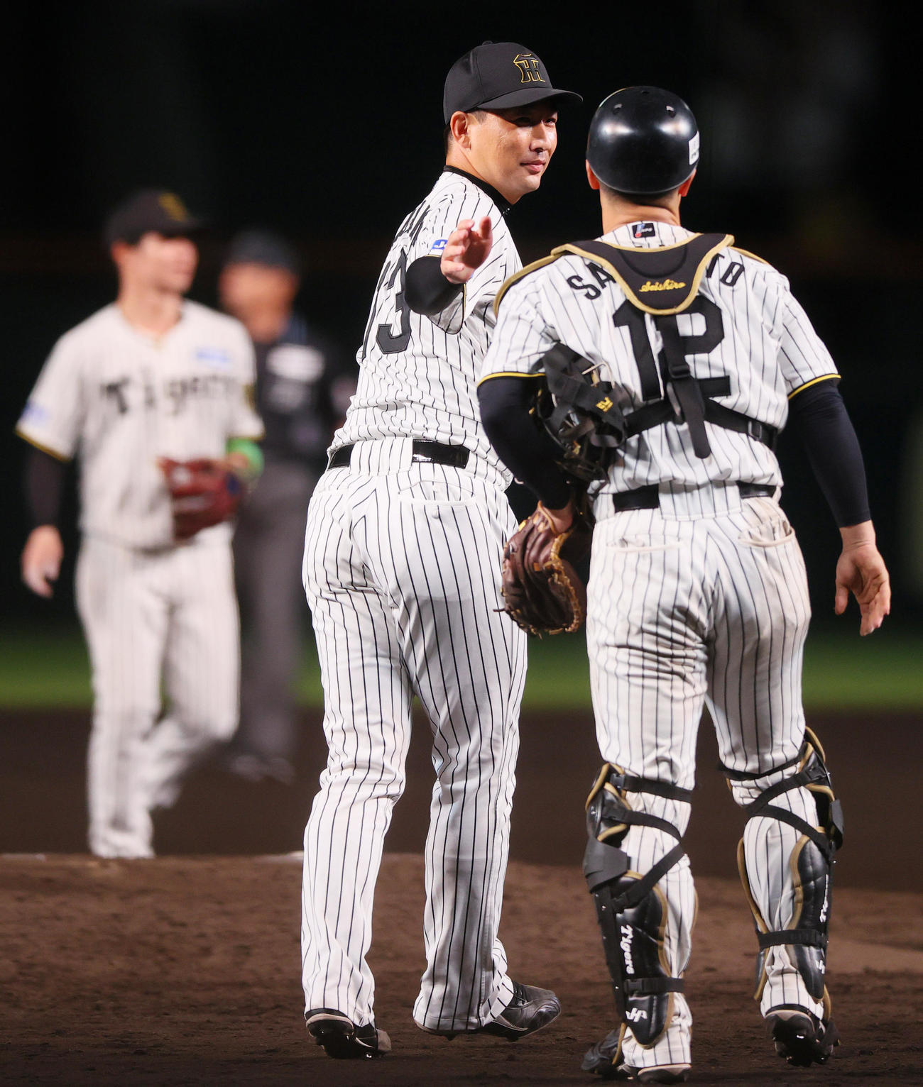 阪神対DeNA　岩崎（中央）は試合を締め坂本とタッチをかわし笑顔を見せる（撮影・上山淳一）