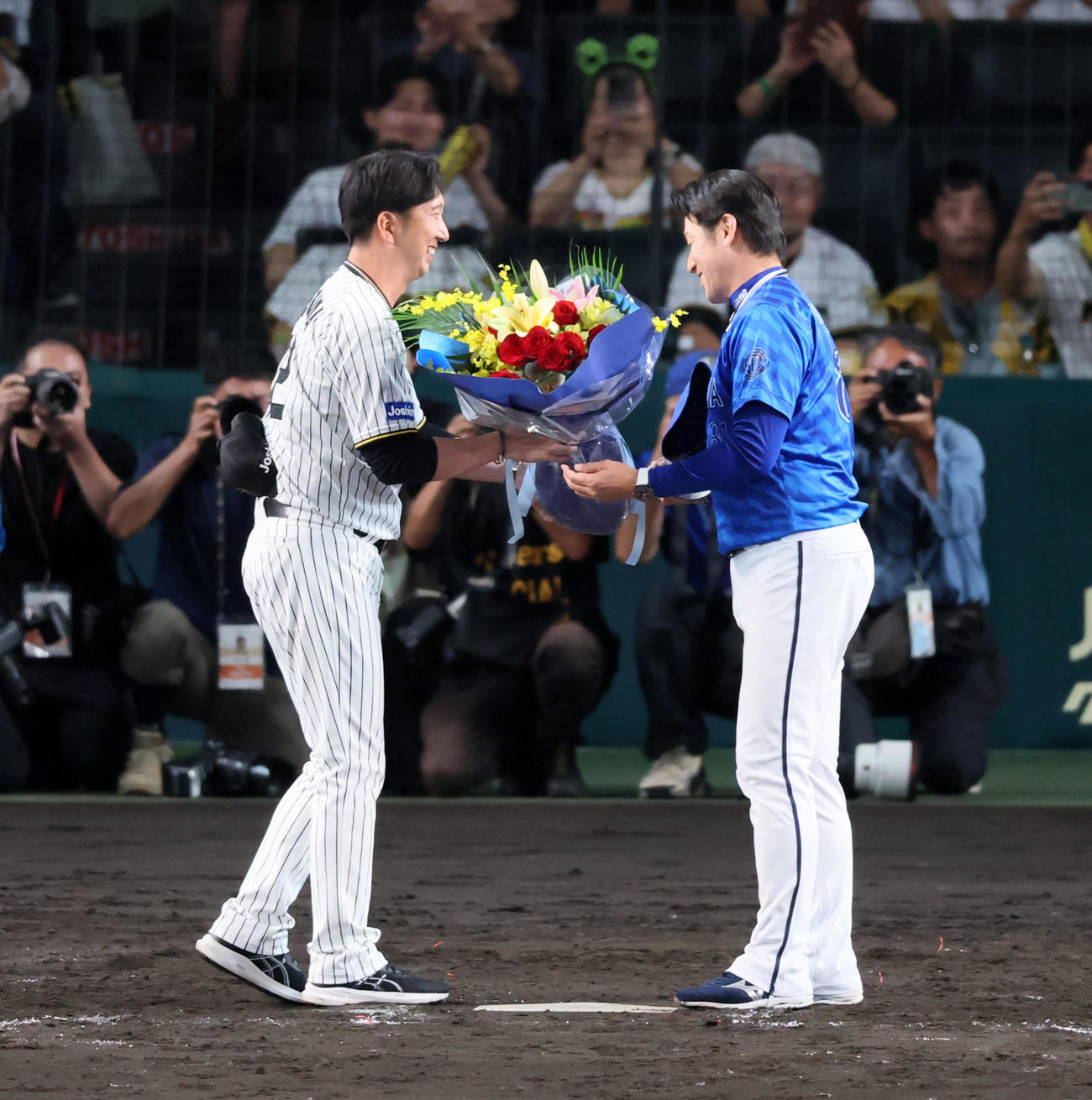 阪神対DeNA　今シーズンで退任するDeNA三浦監督へ阪神藤川監督(左）から花束が贈られた（撮影・加藤哉）