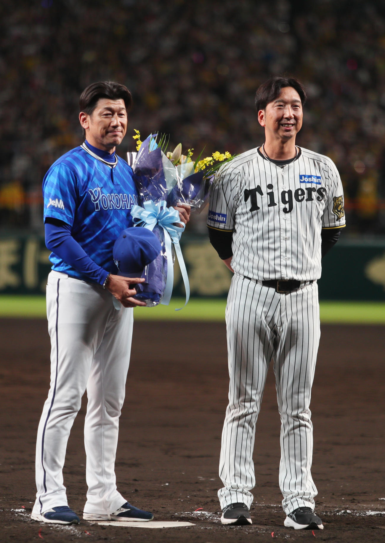 阪神対DeNA　今シーズン限りで退任するDeNA三浦監督（左）は阪神藤川監督から花束を受け取り記念撮影する（撮影・上山淳一）