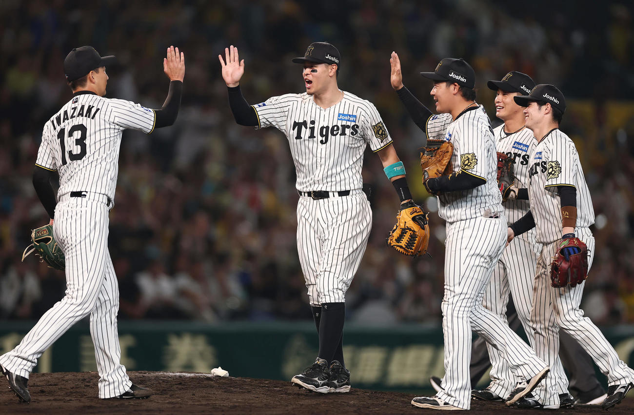阪神対DeNA DeNAを破って日本シリーズ進出を決め、タッチを交わして喜ぶ佐藤輝（左から2人目）ら阪神の選手たち（撮影・前田充）