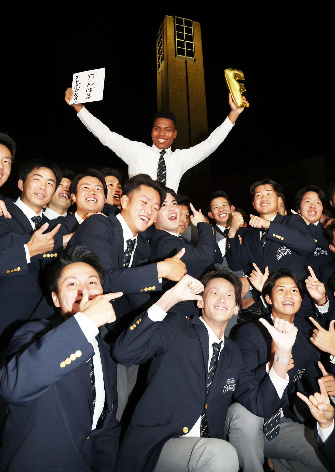 日本ハム2位の大阪学院大エドポロ・ケイン（中）は野球部員に担がれ笑顔を見せる（撮影・西尾就之）