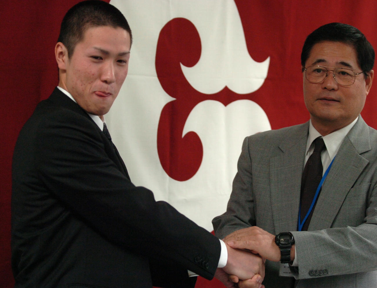 2005年12月5日、育成ドラフト制度で入団した巨人山口哲也（左）は末次利光スカウト部長と握手する