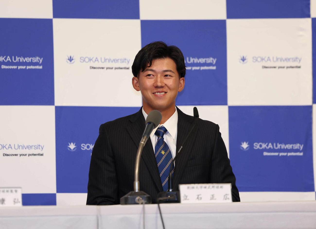 阪神からドラフト1位で指名され部員の方を見てにやっとする創価大・立石（撮影・増田悦実）