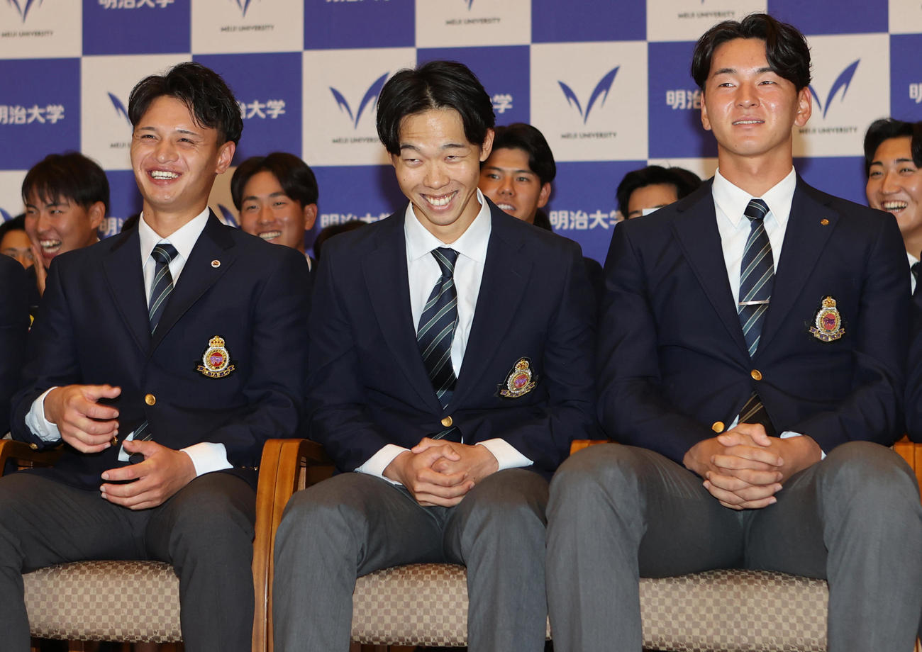 日本ハムにドラフト1位で指名され驚いたような笑顔を見せる明大・大川。左は毛利、右は高須（撮影・水谷安孝）