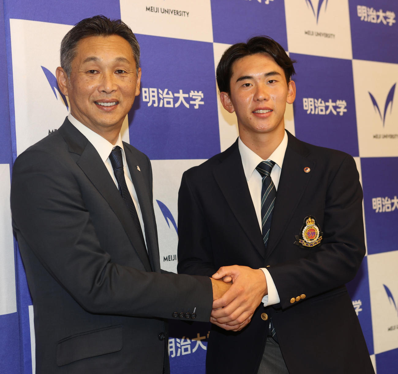 あいさつに訪れた西武西口監督（左）と握手する西武ドラフト1位の明大・小島（撮影・水谷安孝）
