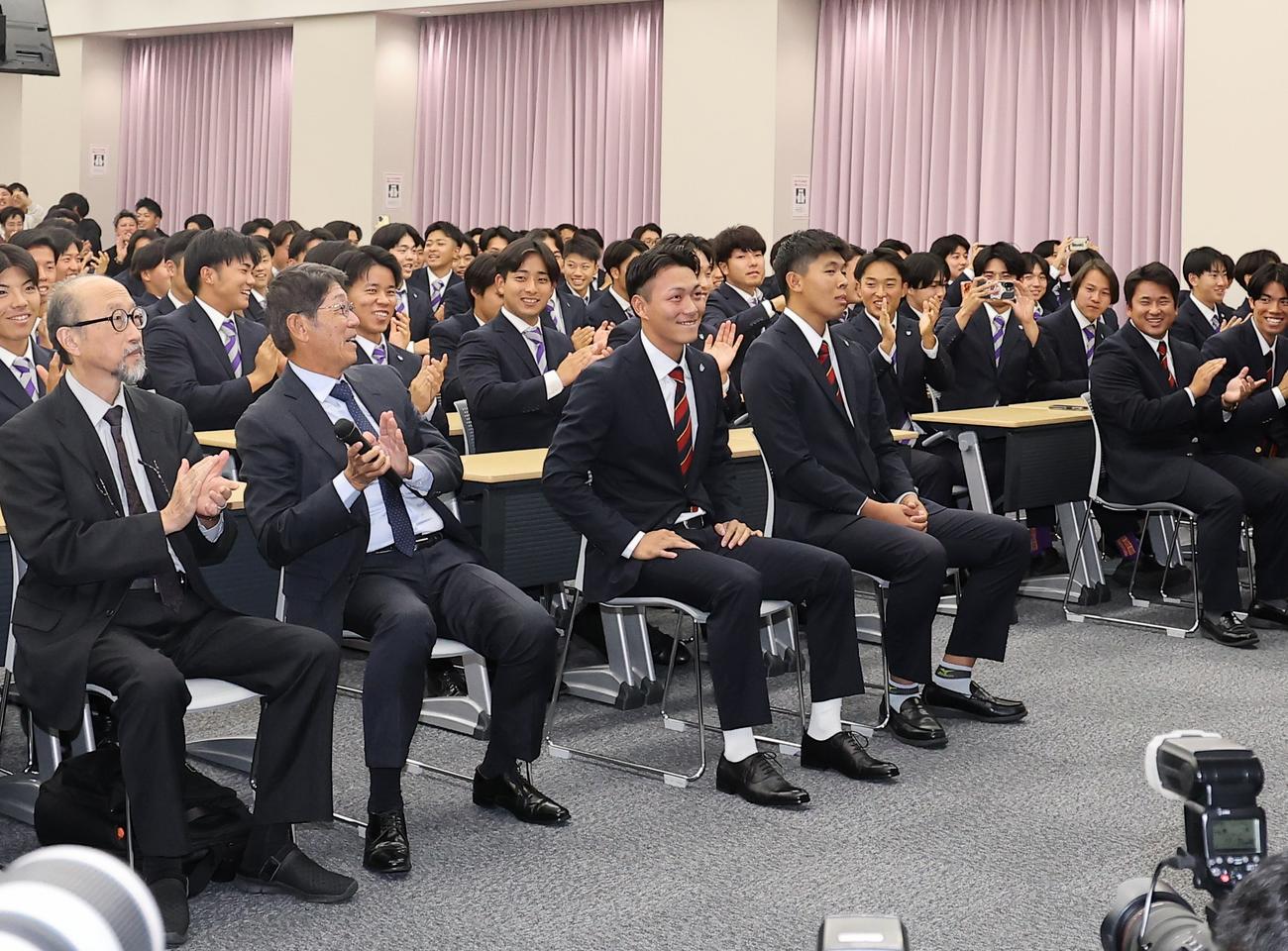 楽天からドラフト1位指名を受けた花園大・藤原（中央）は笑顔を見せる（撮影・上田博志）