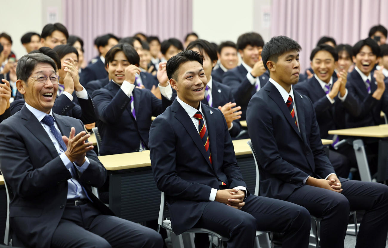 楽天からドラフト1位指名を受けた花園大・藤原（中央）は笑顔を見せる（撮影・上田博志）