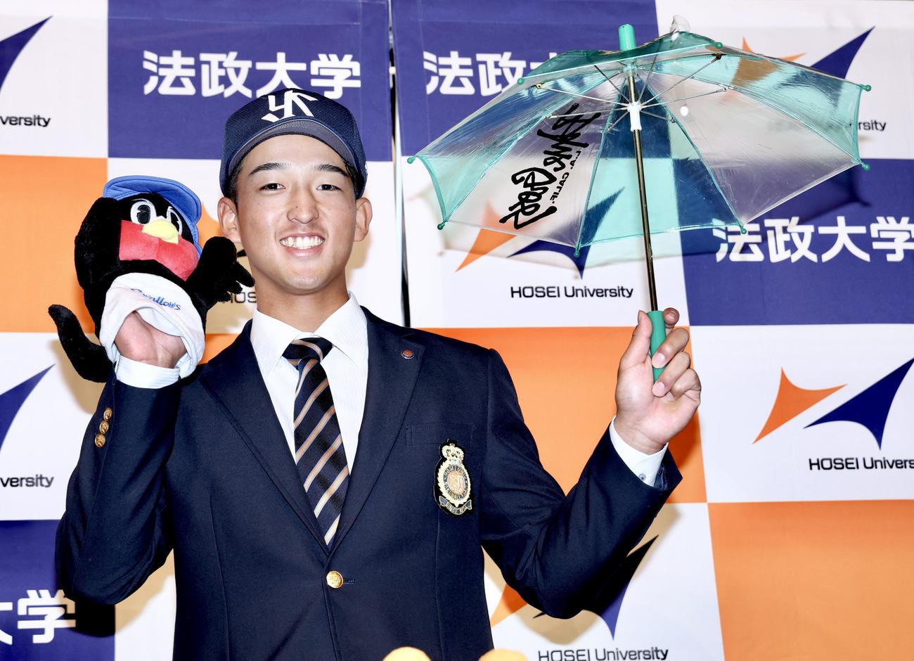 グッズを手に笑顔で写真に納まるヤクルトドラフト1位指名を受けた法大・松下（撮影・河田真司）