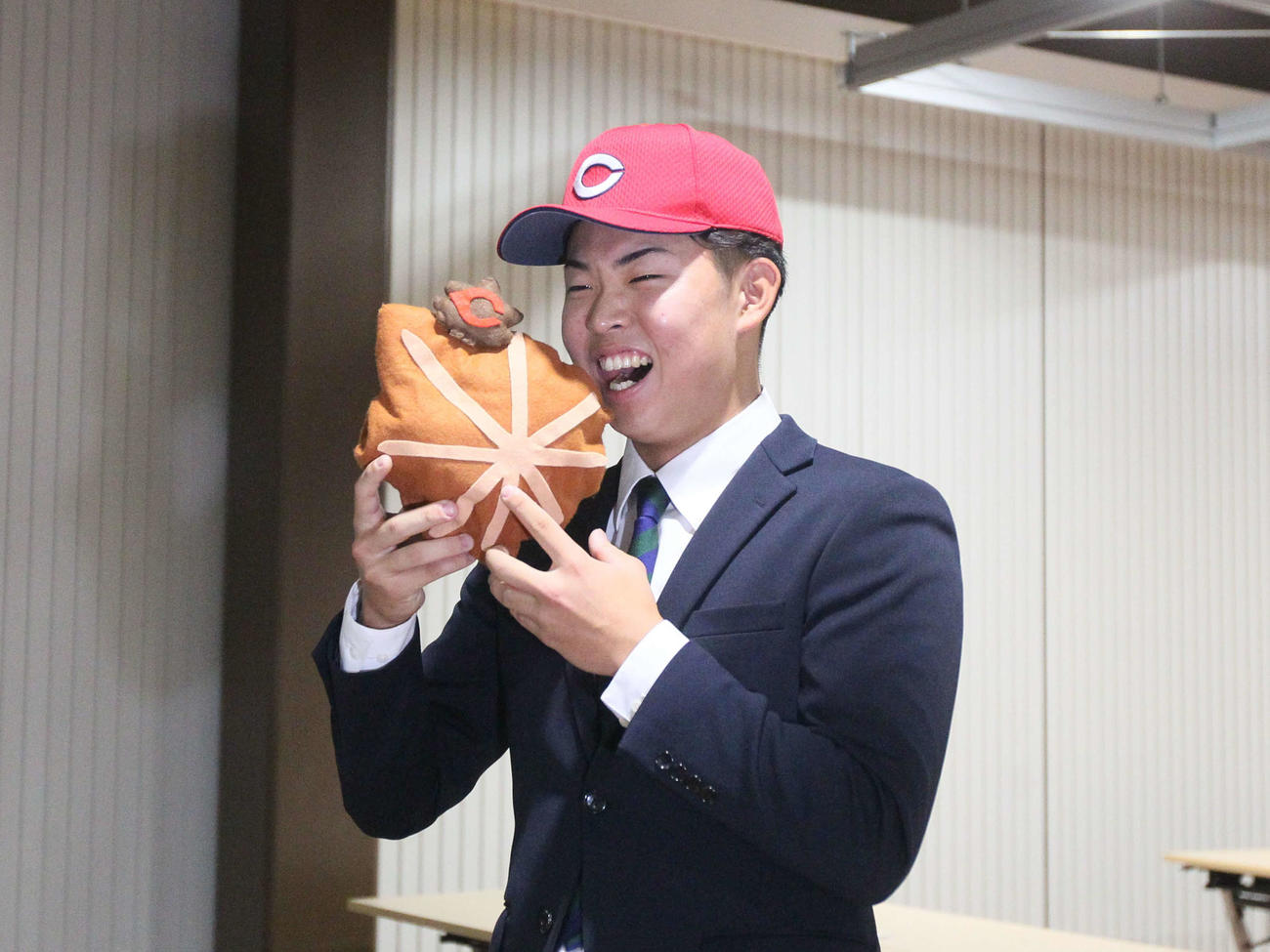 広島の帽子をかぶり広島銘菓もみじまんじゅうのぬいぐるみにかぶりつく仙台大・平川（撮影・高橋香奈）