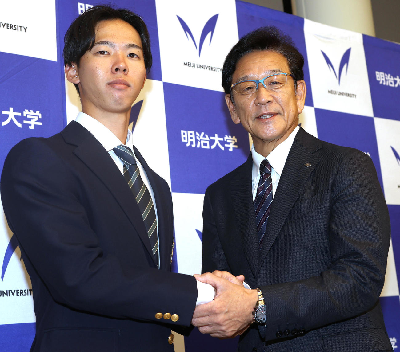 あいさつに訪れた日本ハム栗山CBO（右）と握手する日本ハムドラフト1位の明大・大川（撮影・水谷安孝）