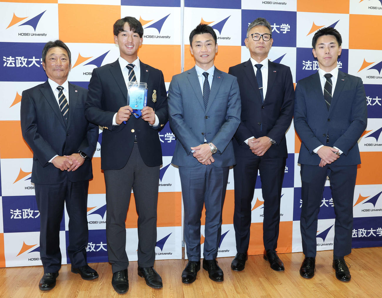 指名あいさつを受け、笑顔で記念撮影する法大・大島監督、ヤクルトドラフト1位の松下、青木GM特別補佐、橿渕スカウトグループデスク、余田スカウト（撮影・宮地輝）