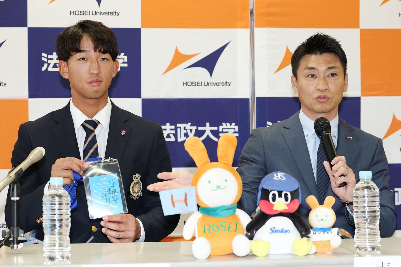 指名あいさつを受け、ヤクルト池山監督の直筆メッセージ入りパスを青木GM特別補佐（右）から受け取ったドラフト1位の法大・松下（撮影・宮地輝）