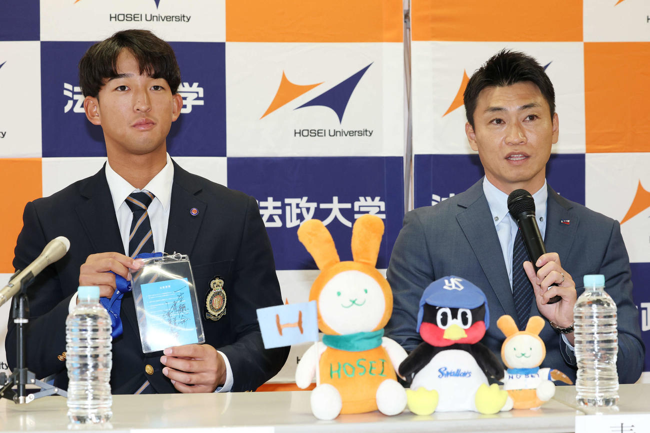 指名あいさつを受け、ヤクルト池山監督の直筆メッセージ入りパスを青木GM特別補佐（右）から受け取ったドラフト1位の法大・松下（撮影・宮地輝）