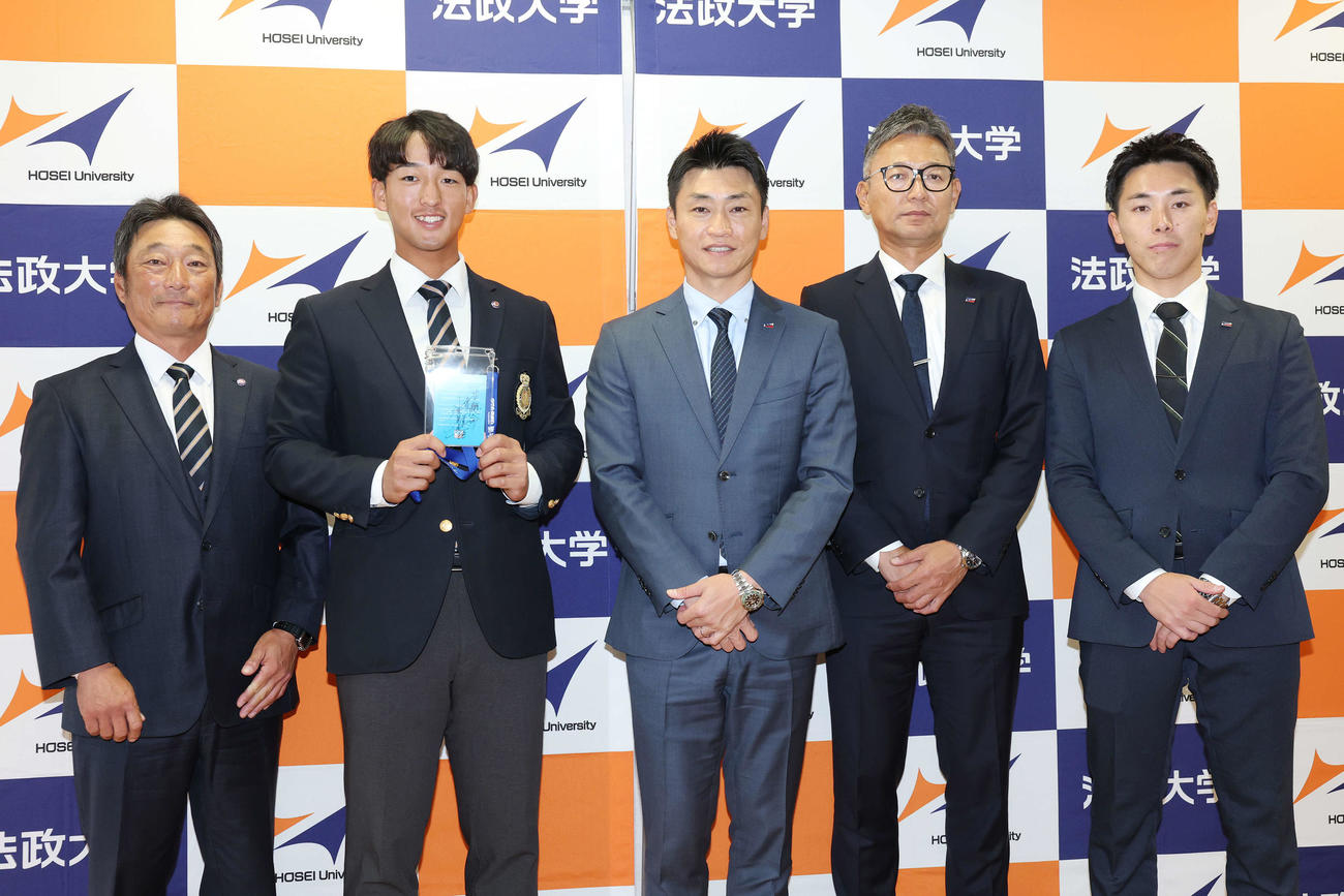 指名あいさつを受け、笑顔で記念撮影する法大・大島監督、ヤクルトドラフト1位の松下、青木GM特別補佐、橿渕スカウトグループデスク、余田スカウト（撮影・宮地輝）