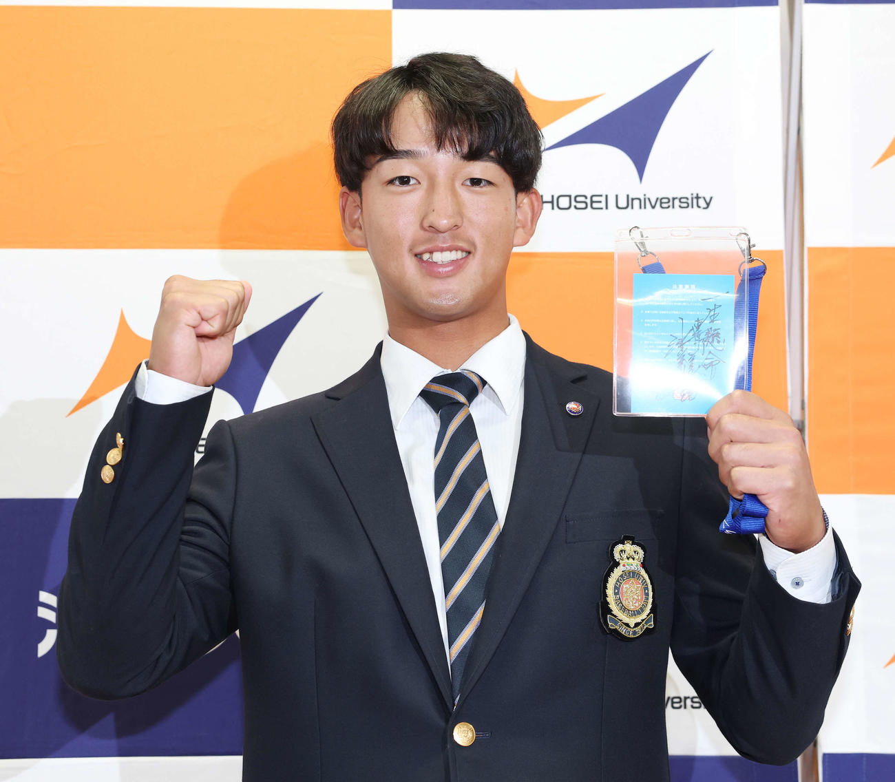 指名あいさつを受け、ヤクルト池山監督の直筆メッセージ入りパスを手に笑顔を見せるドラフト1位の法大・松下（撮影・宮地輝）