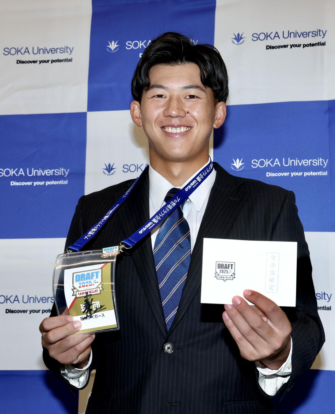 阪神藤川監督のサインが入ったドラフト会議2025のIDと交渉権確定の印が押されたくじを手に笑顔で写真に納まる創価大・立石（撮影・河田真司）