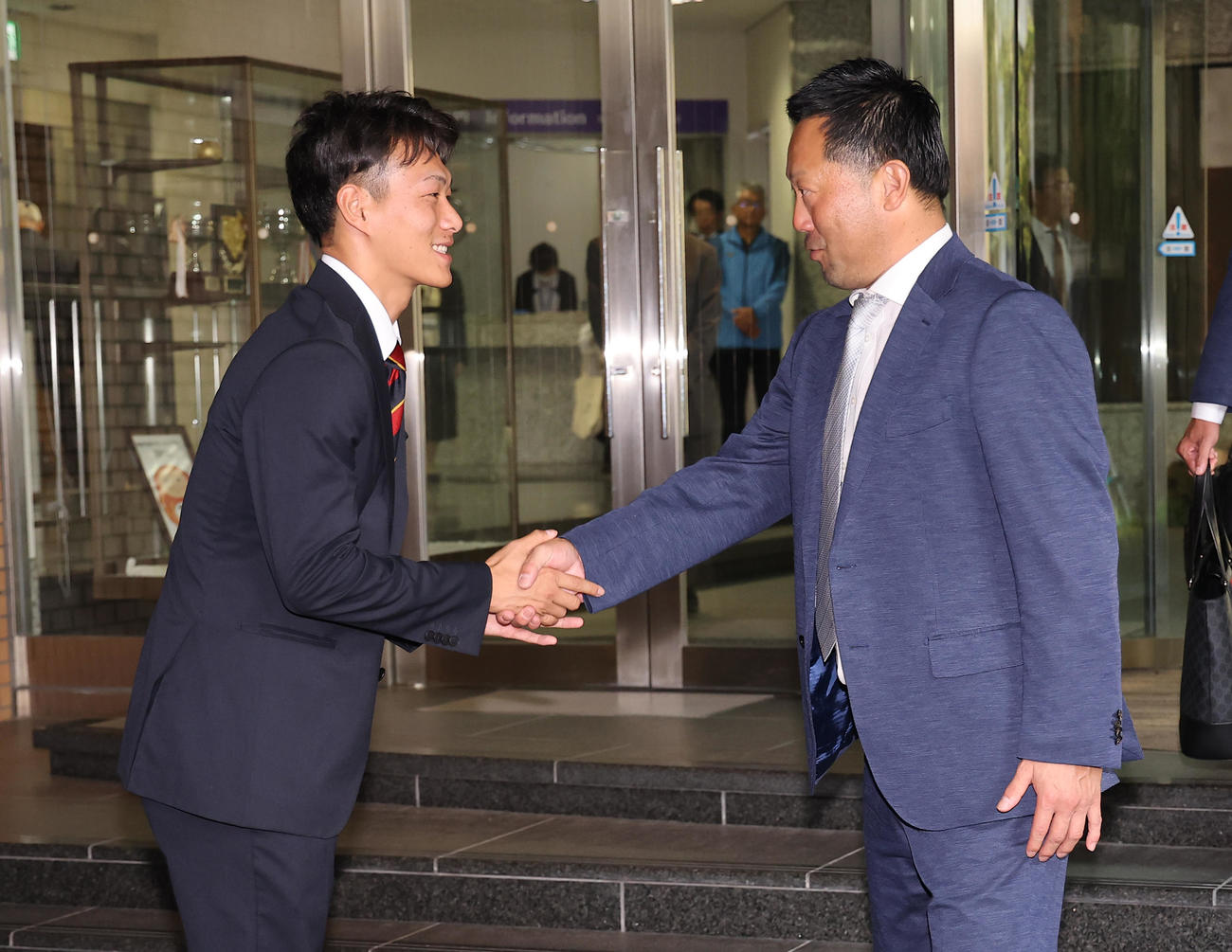 楽天から1位指名を受けた花園大・藤原（左）は三木監督とあくしゅを交わす（撮影・上田博志）