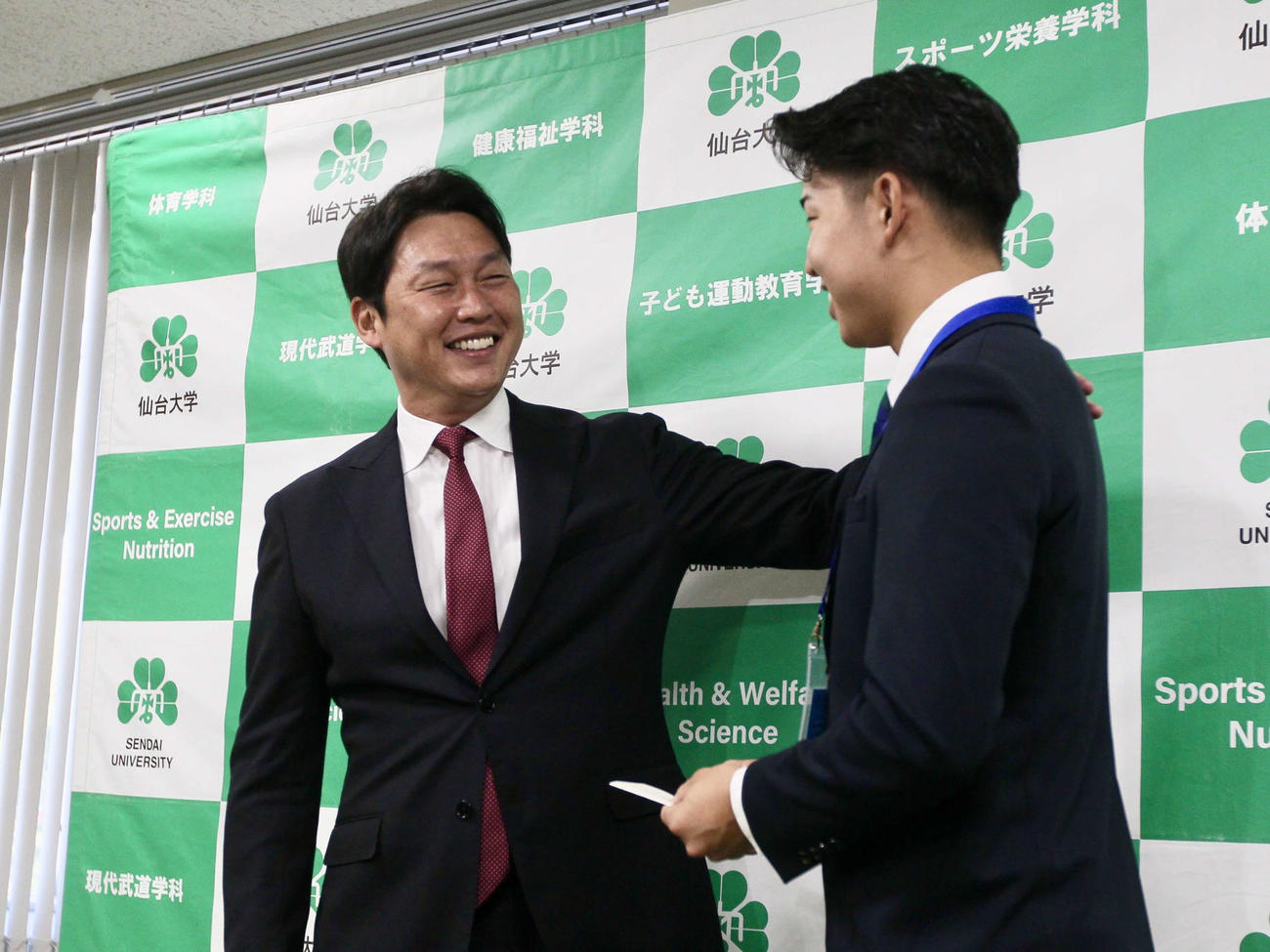 仙台大・平川に交渉権確定のくじを渡し微笑みかける広島・新井監督（撮影・高橋香奈）