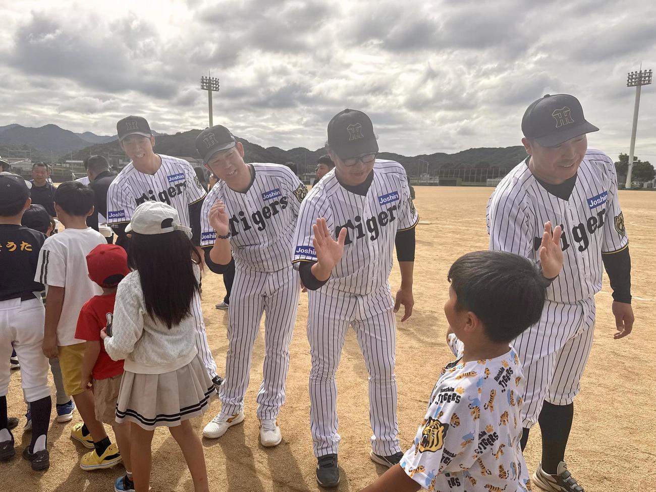淡路島野球教室で子どもたちとハイタッチする右から元阪神の森田一成氏、福原忍氏、岩田稔氏、岩本輝氏（提供写真）