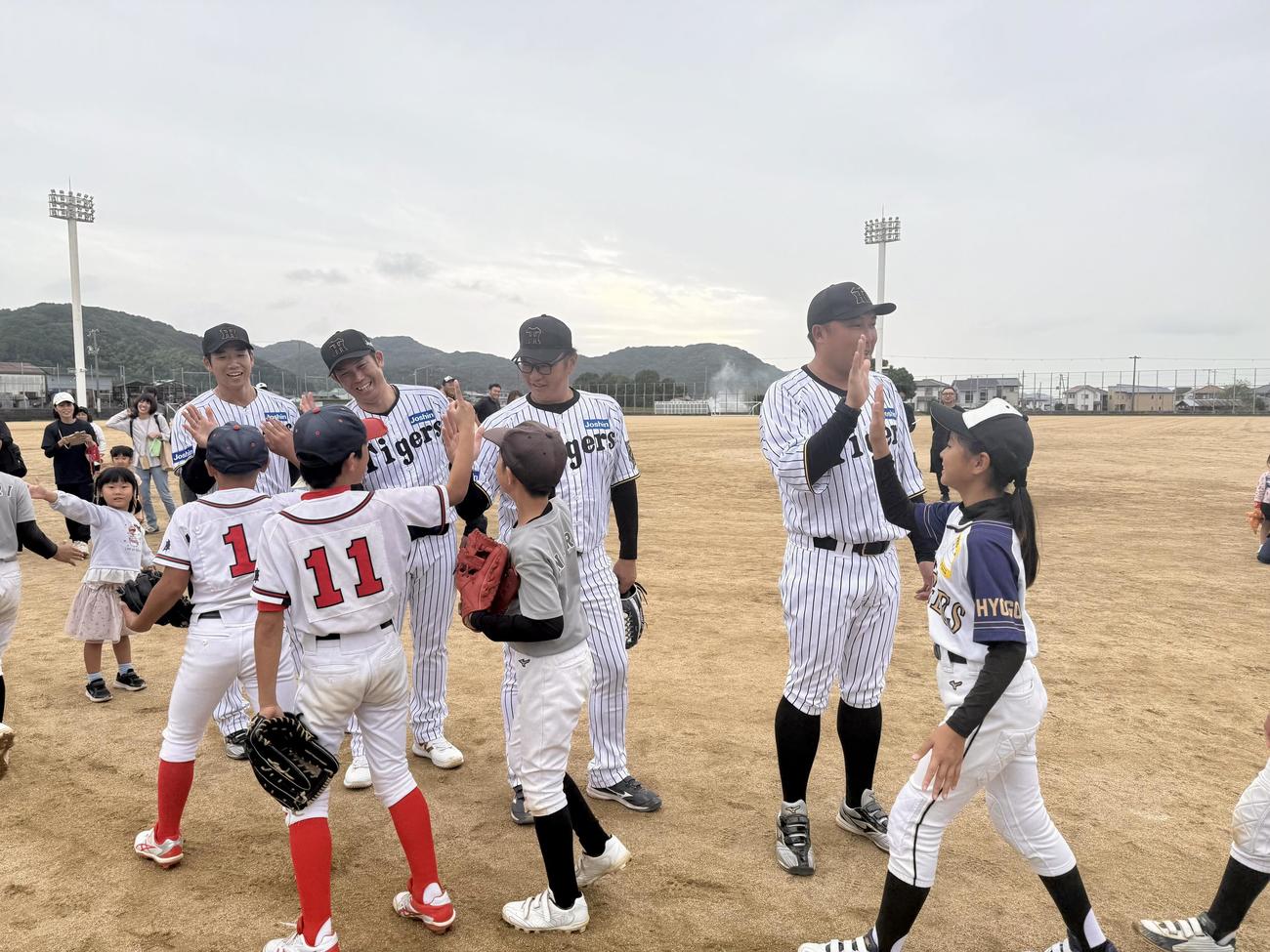 淡路島野球教室で子どもたちとハイタッチする右から元阪神の森田一成氏、福原忍氏、岩田稔氏、岩本輝氏（提供写真）