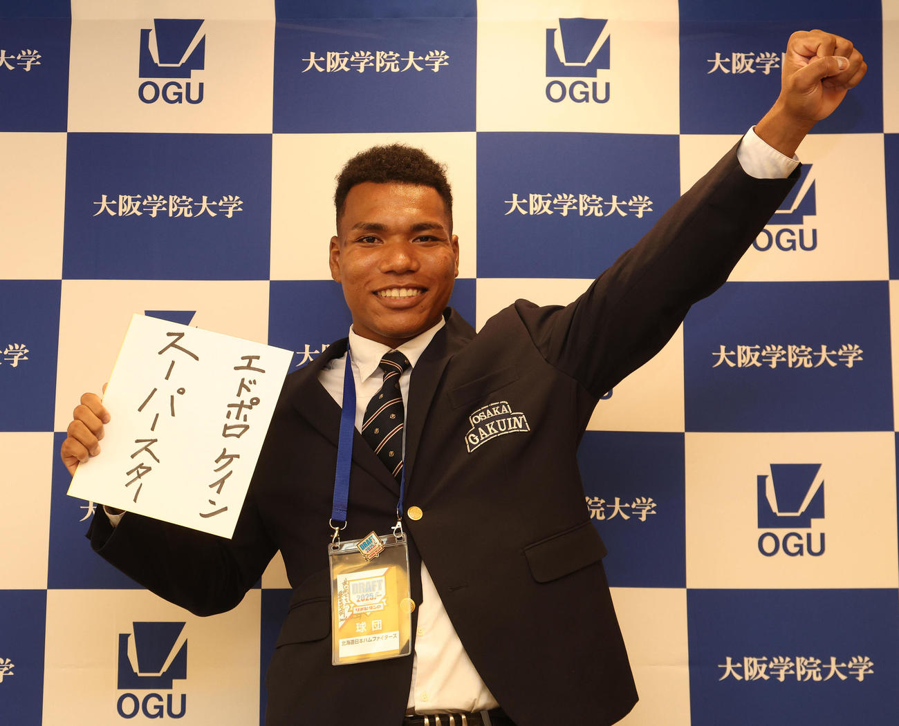 スーパースターと書かれた色紙を手にガッツポーズする大阪学院大エドポロケイン（撮影・白石智彦）