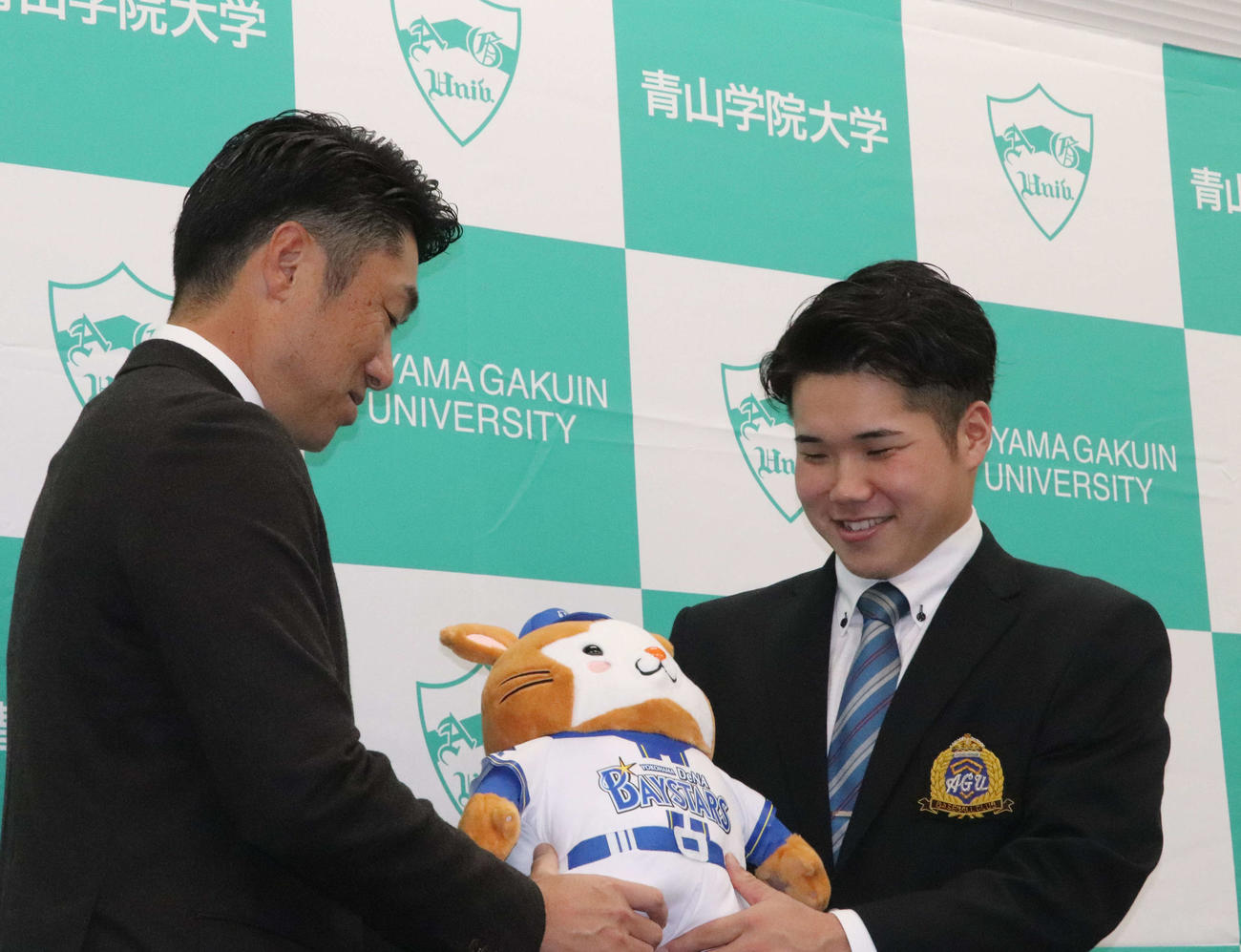 指名あいさつを受けたDeNAドラフト1位の青学大・小田は球団マスコットのDB・スターマンをプレゼントされて笑顔を見せる（撮影・小早川宗一郎）